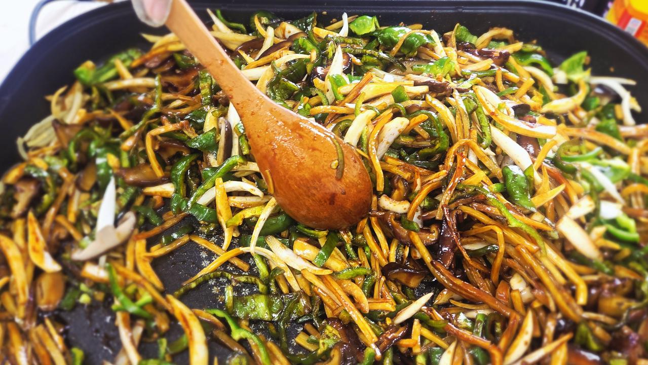 나무 주걱으로 맛있게 조리된 고추잡채를 부드럽게 섞고 있는 장면