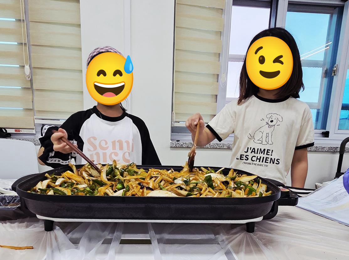 두 아이가 전기 그릴 팬 앞에서 함께 고추잡채를 만들며 협동하는 모습
